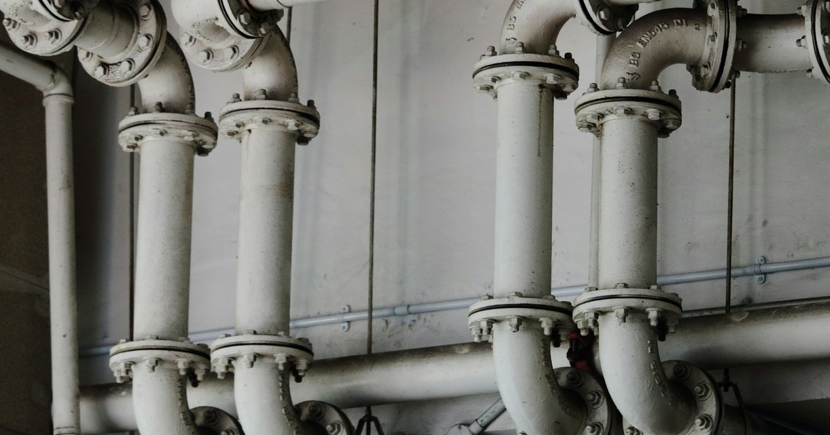 Red de tuberías industriales metálicas en escala de grises, mostrando la infraestructura de conexiones necesaria para que el sistema funcione