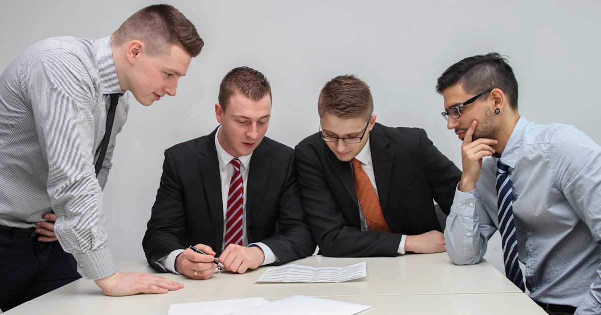Four people around a table reviewing a printed document together