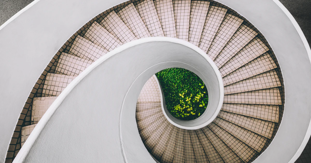 White and brown spiral staircase seen from below, with steps ascending in a spiral toward the light