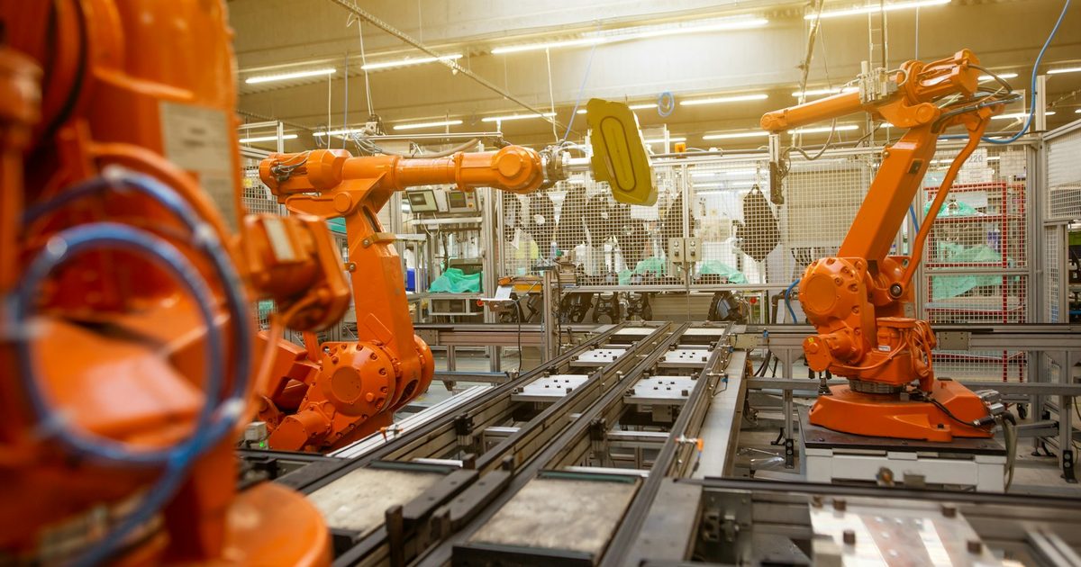 Brazos robóticos naranjas en planta de ensamblaje industrial automatizada en Olomouc, República Checa