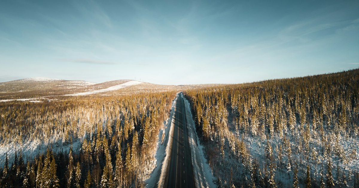 Vista aérea de una carretera solitaria que atraviesa un campo nevado — infraestructura intacta, sin tráfico a la vista