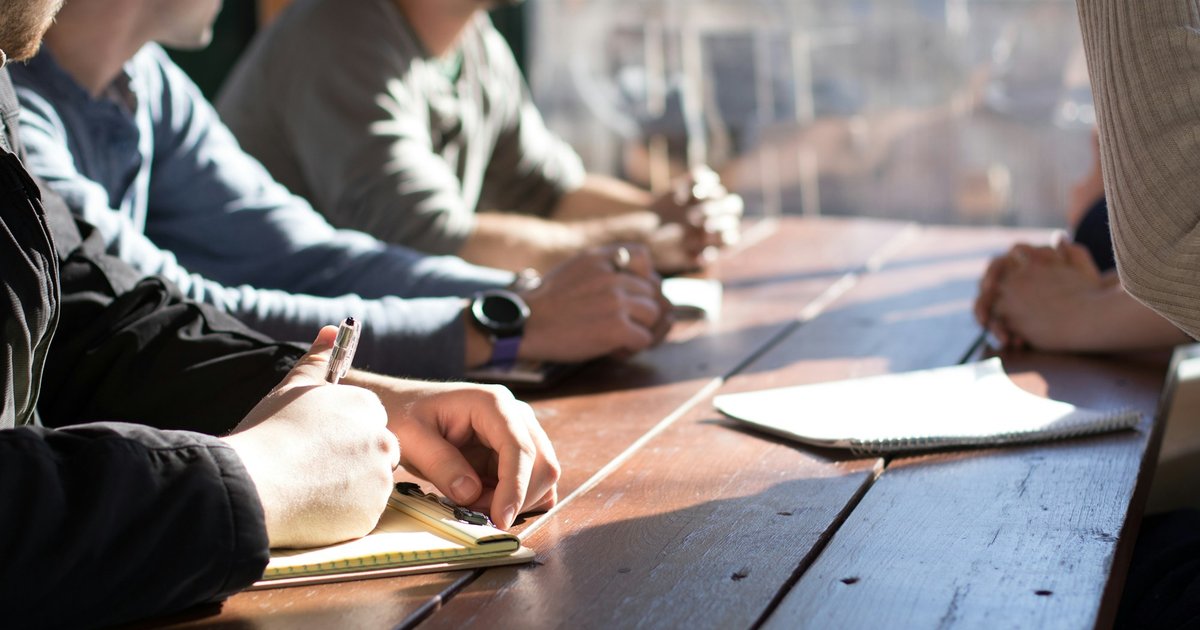 Profesionales reunidos alrededor de una mesa de reuniones, tomando notas y discutiendo estrategia en un entorno corporativo