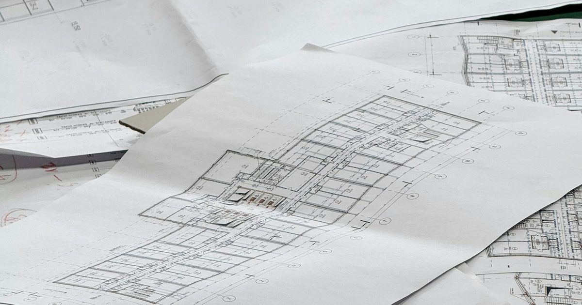 Planos arquitectónicos desplegados sobre una superficie, mostrando detalles técnicos de diseño de construcción